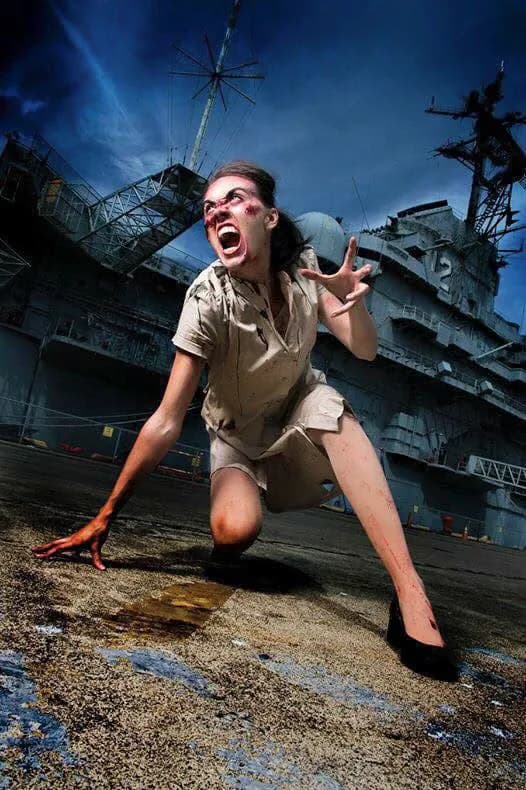 A screaming woman crawling across the deck as the USS Hornet looms under a stormy sky.